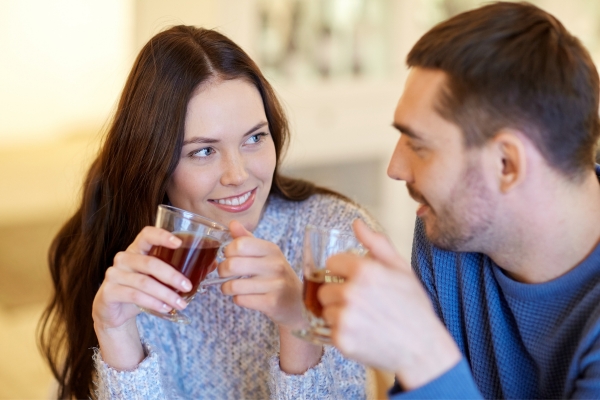 happy couple looking at one another in romantic mood with cup of tea in hands in home